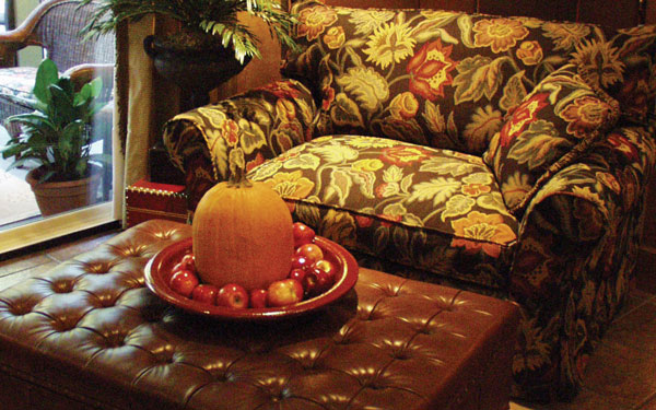 A pumpkin and group of apples resting on a tray that sits on top of an automan.